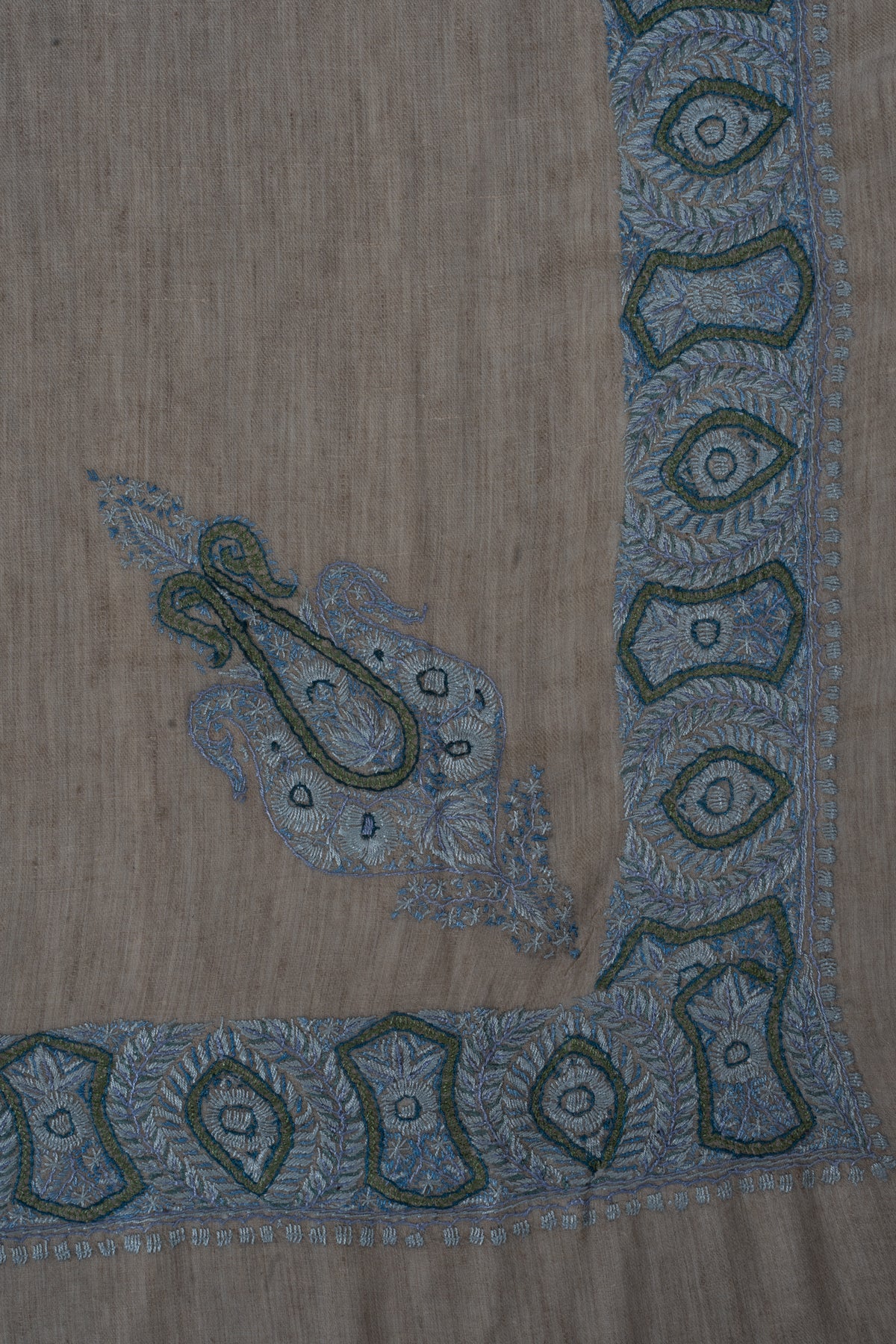 Taupe-beige rumal corner with a small blue and sage motif inside the geometric border