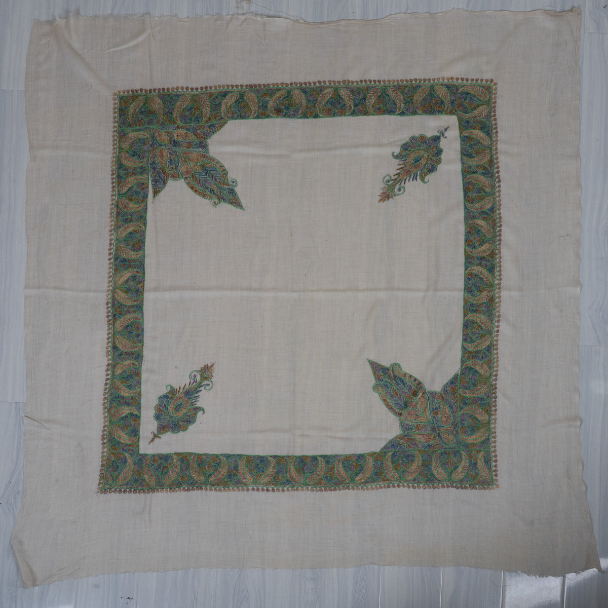 Ivory cashmere rumal laid flat, with green-blue leaf borders, two large and two smaller corner designs