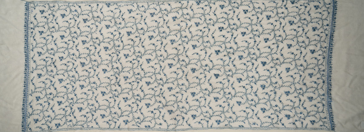 Ivory stole spread flat, showing a repeating blue floral vine field framed by narrow embroidered borders