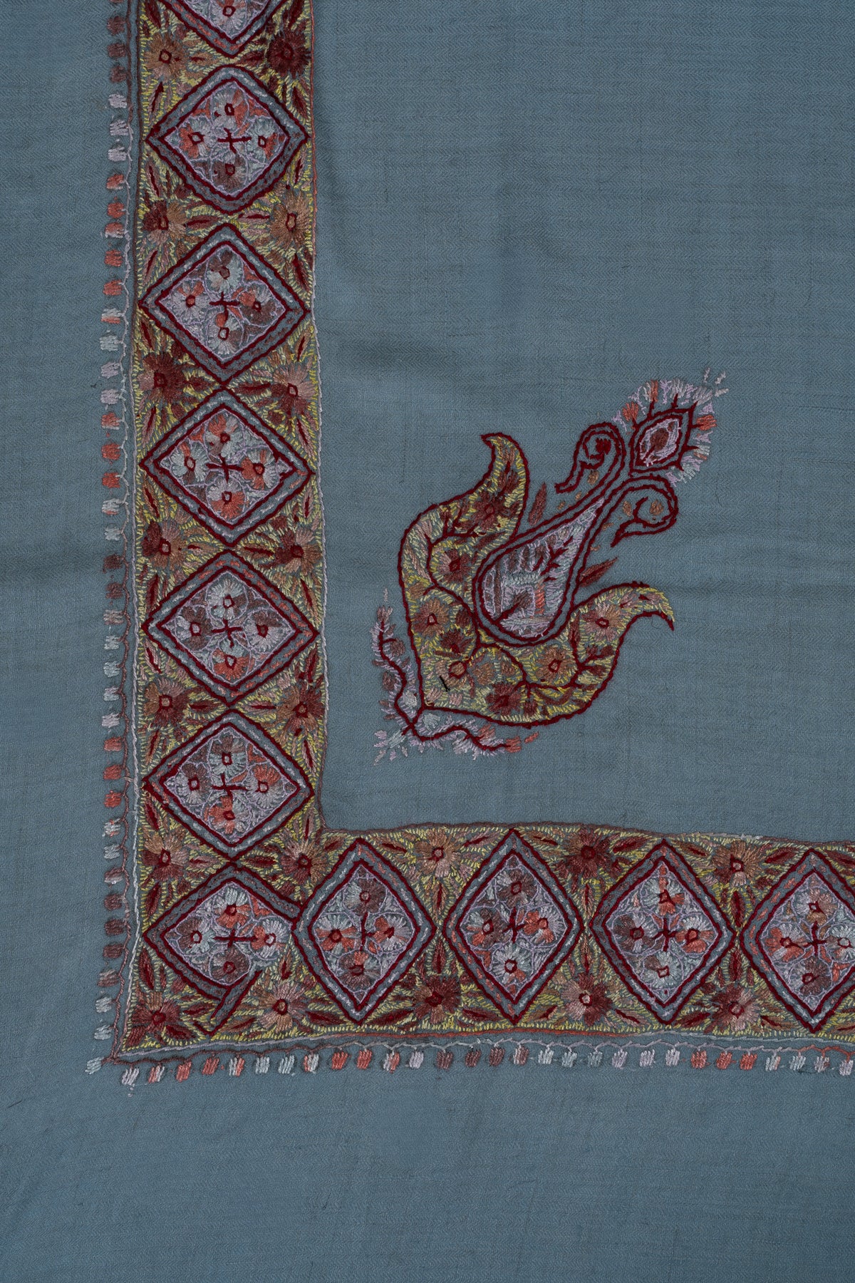 Corner of a sky-blue cashmere rumal with a garnet and gold Sozni paisley inside diamond-panel borders.