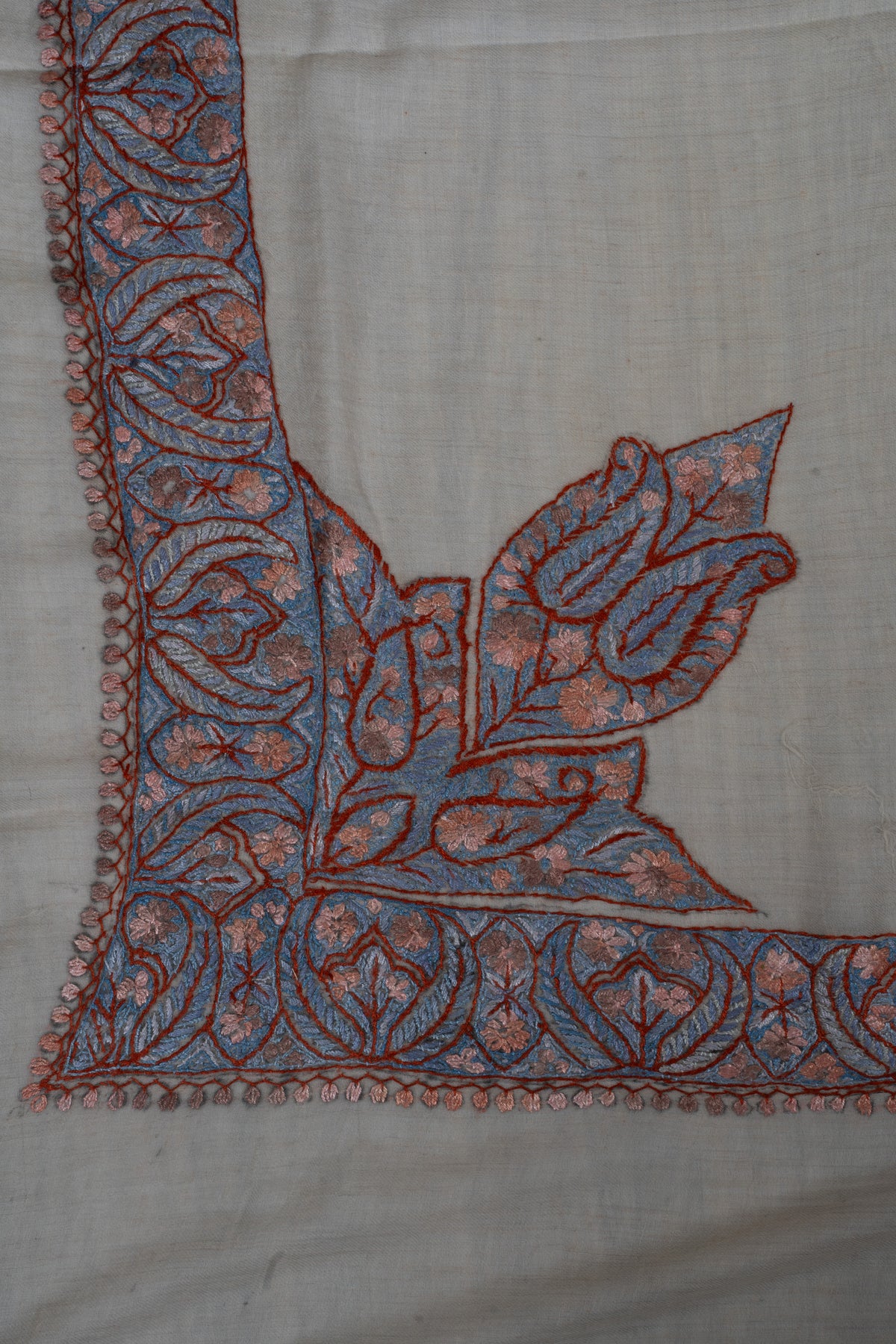Large blue Sozni leaves with dusky-rose flowers rise from the border at one corner of a beige cashmere rumal.
