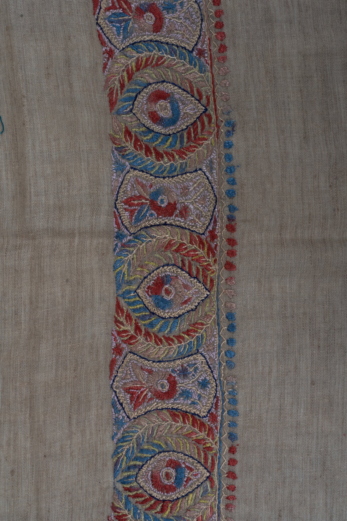 Close-up of alternating crimson and blue floral shapes and fern-like leaves in the rumal's border