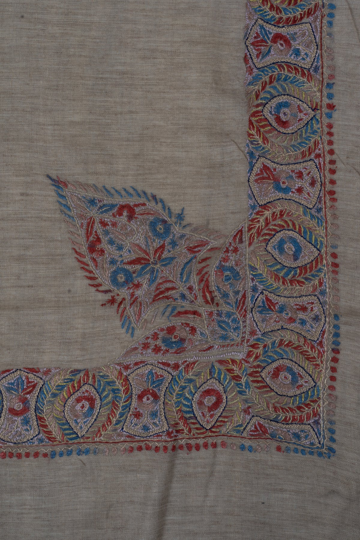 Taupe rumal corner with a large pointed floral design extending from the crimson-blue border