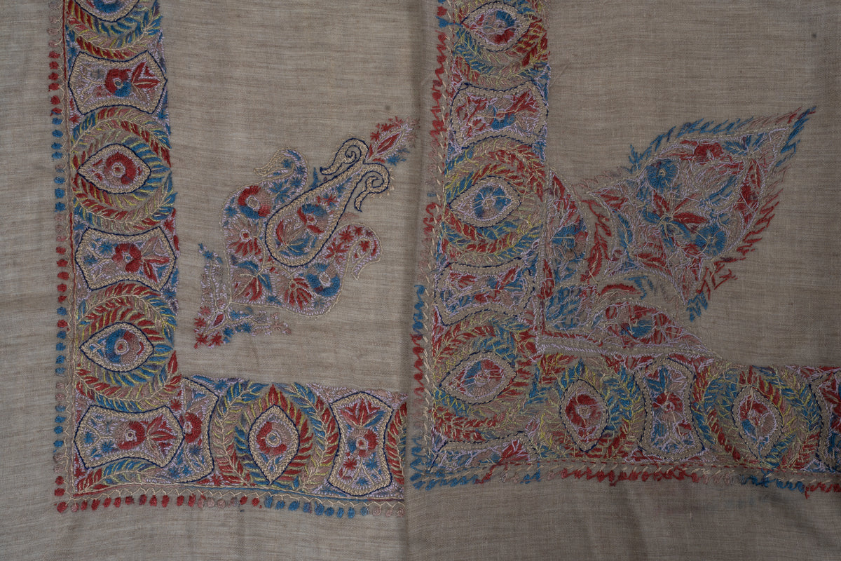 Overlapping taupe rumal corners showing a smaller curled motif beside the large pointed floral design