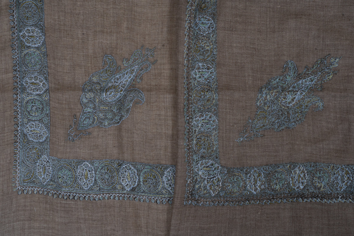 Two mushroom-brown cashmere rumal corners showing blue-grey paisleys and the front and reverse of Sozni border stitching.
