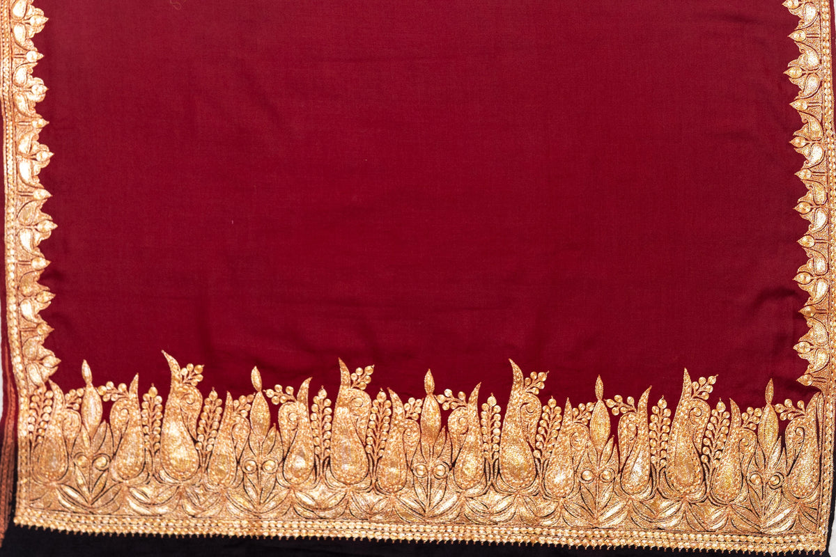 Crimson shawl laid flat with a plain centre, narrow gold-coloured side borders and an ornate paisley end band.