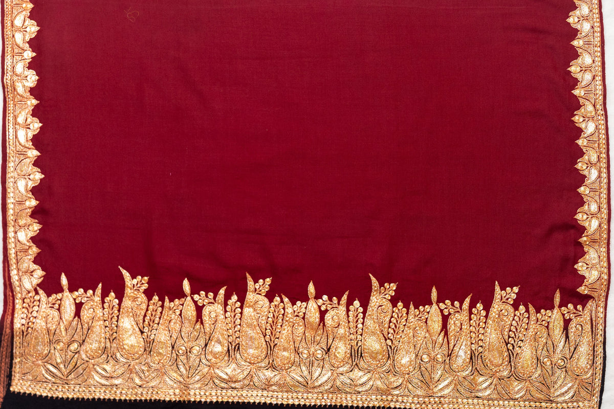 Flat view of the crimson shawl end showing a broad gold-coloured paisley and leaf border beneath the plain field.