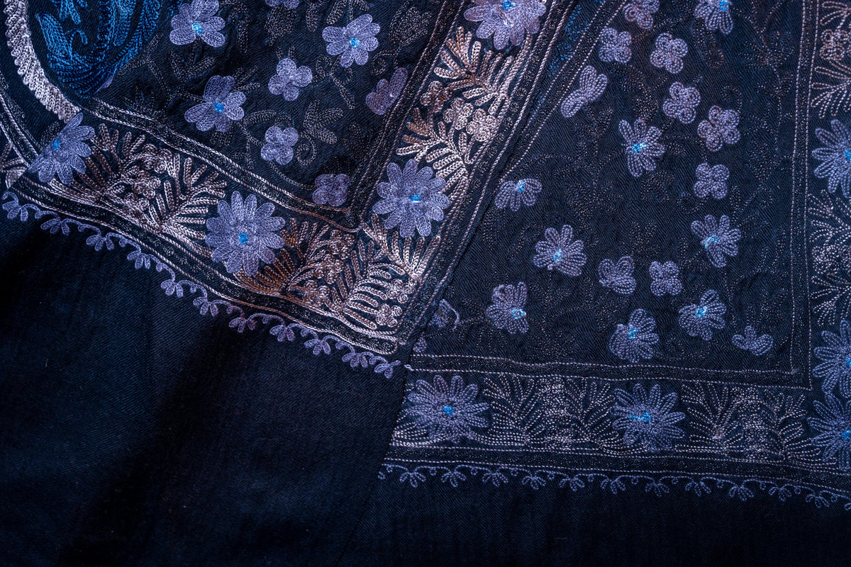 Overlapping black stole corners showing blue floral embroidery and the reverse of the silver-toned border