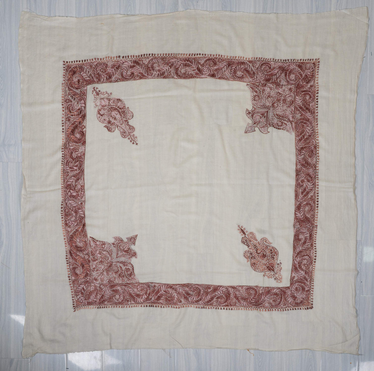 Ivory rumal laid flat, with dusty-rose paisley borders, two large corner panels and two smaller motifs