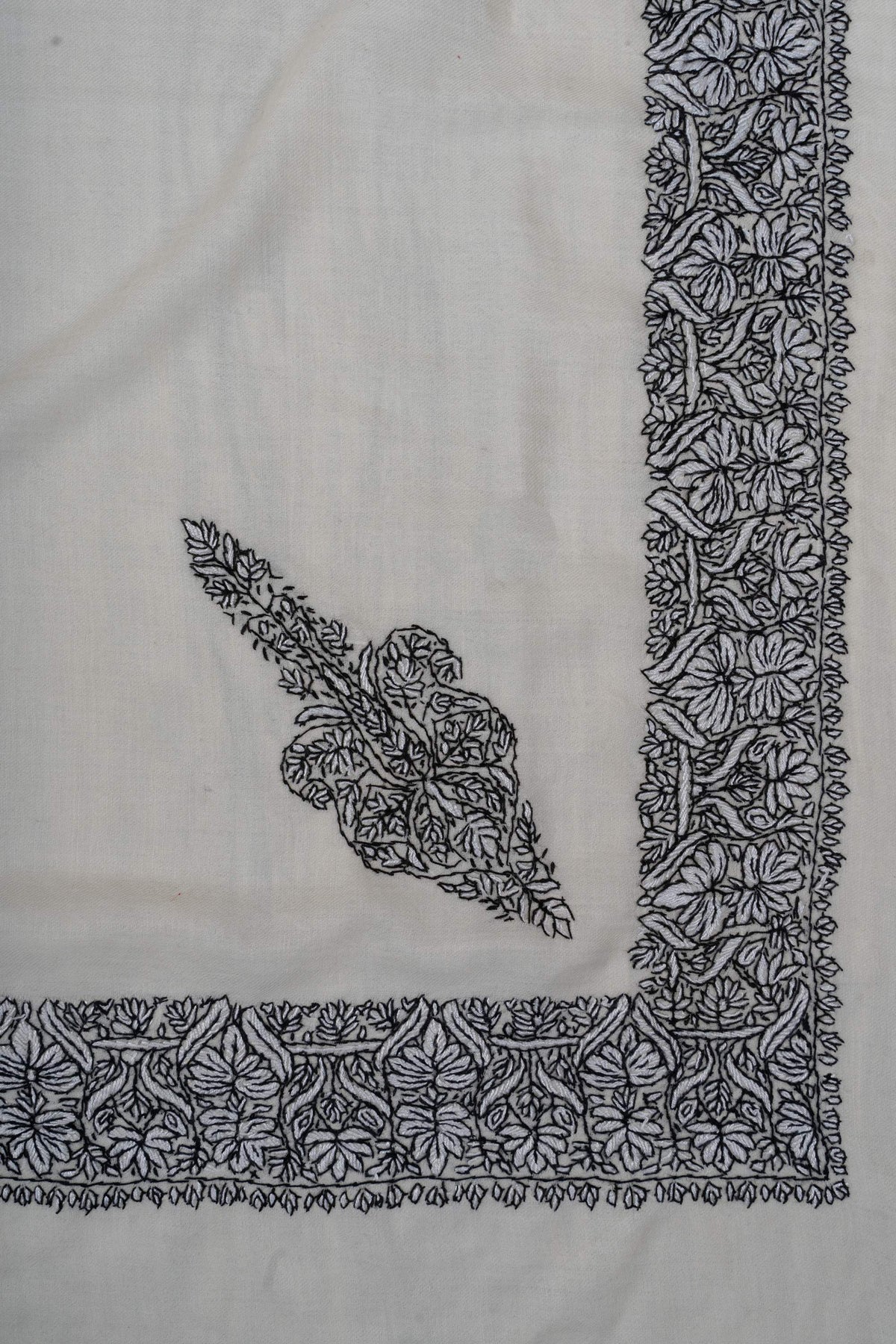 Ivory rumal corner with a separate elongated black Sozni floral motif beside a broad embroidered border