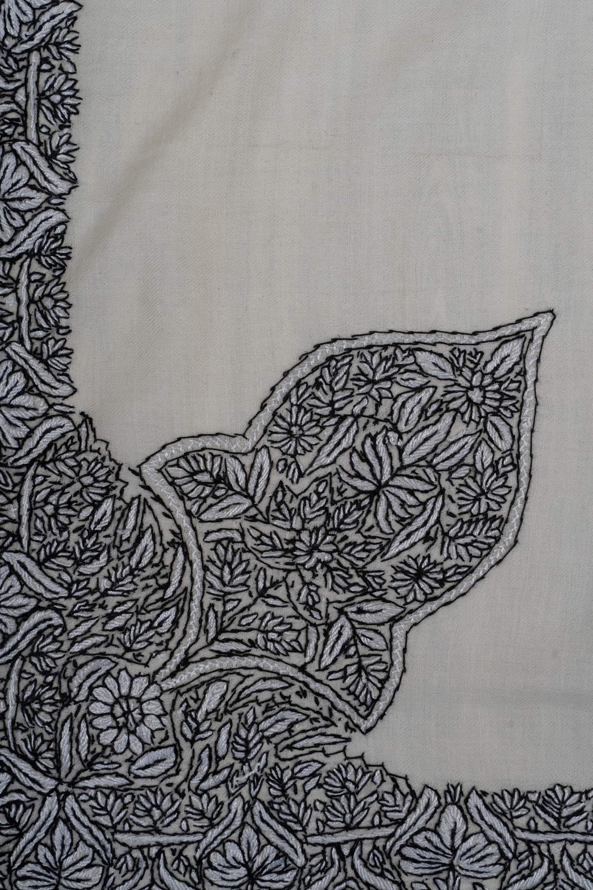 Large leaf-shaped Sozni corner motif densely filled with black flowers and leaves, joined to the rumal border