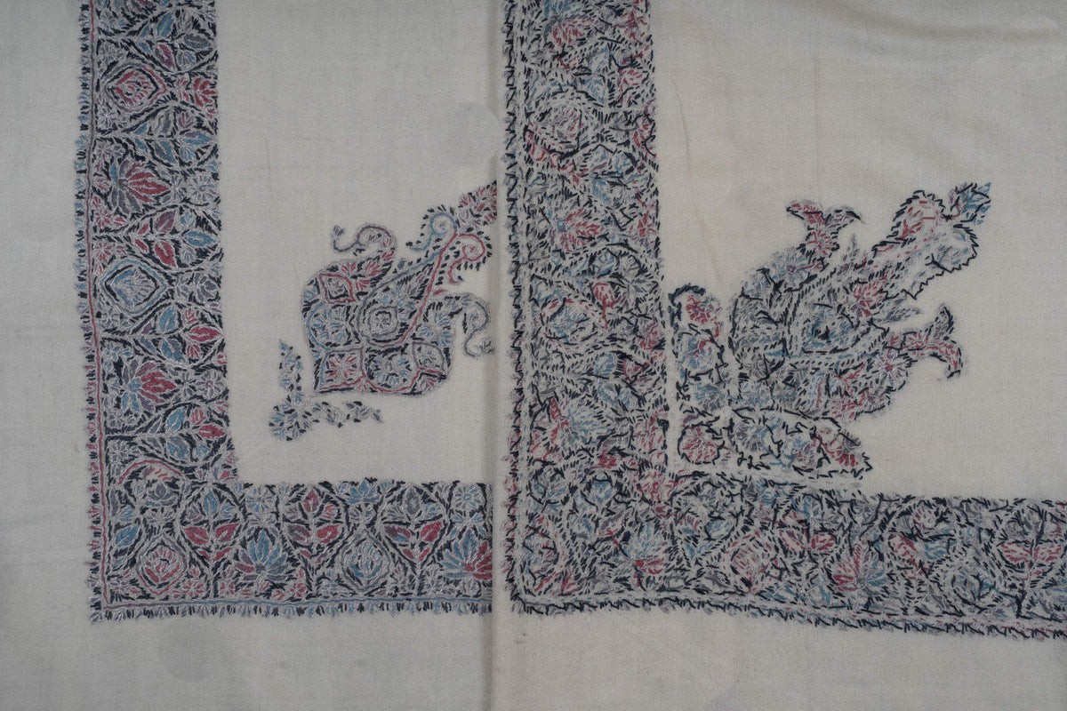 Overlapping ivory rumal corners showing the smaller motif beside the larger floral corner design