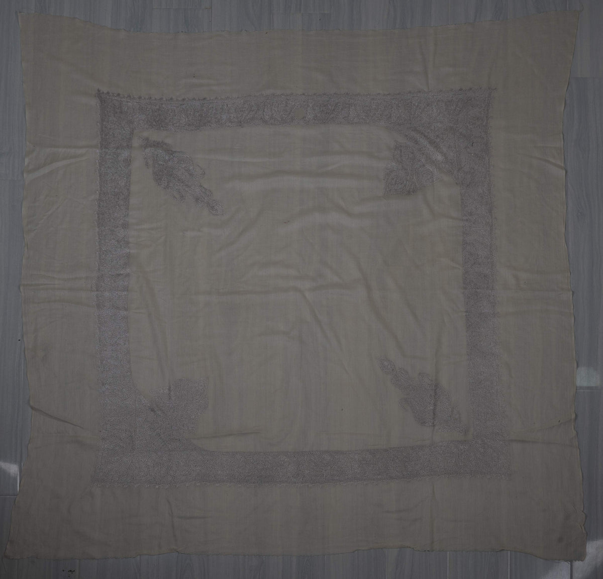 Ivory square Merino wool rumal laid flat with silver-grey Sozni borders, two separate motifs and two large leafy corners.