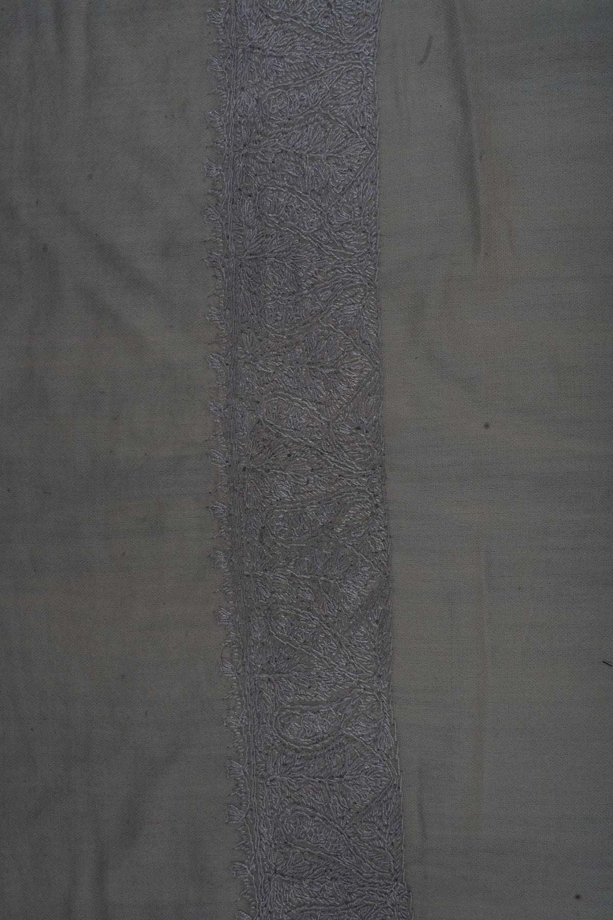Close-up of a silver-grey Sozni border filled with dense scrolling flowers and leaves on ivory Merino wool.