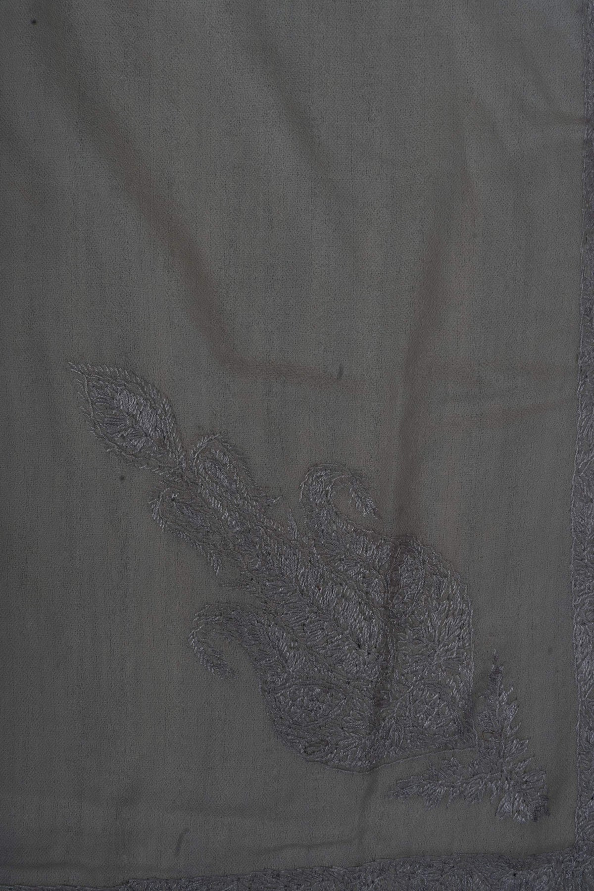 Close-up of an ornate silver-grey Sozni motif filled with fine flowers and curling leaves on ivory Merino wool.