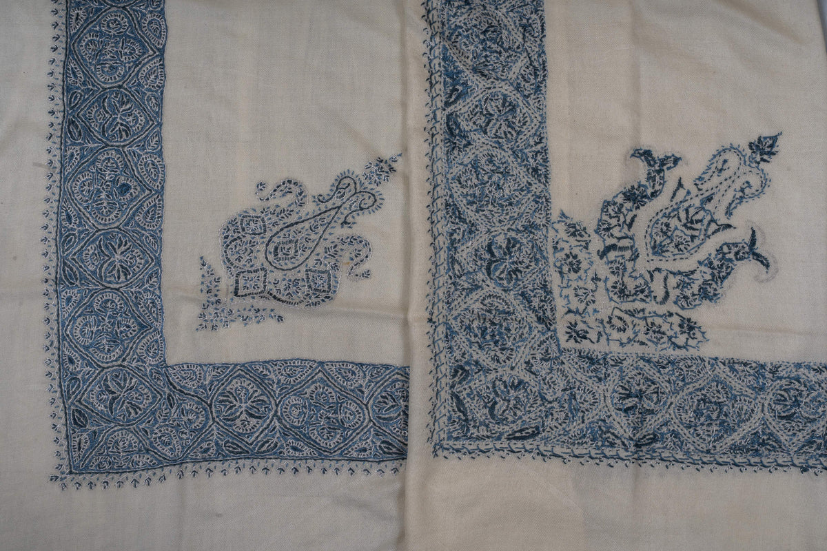 Folded ivory rumal corners displaying both sides of the indigo paisley and floral embroidery.