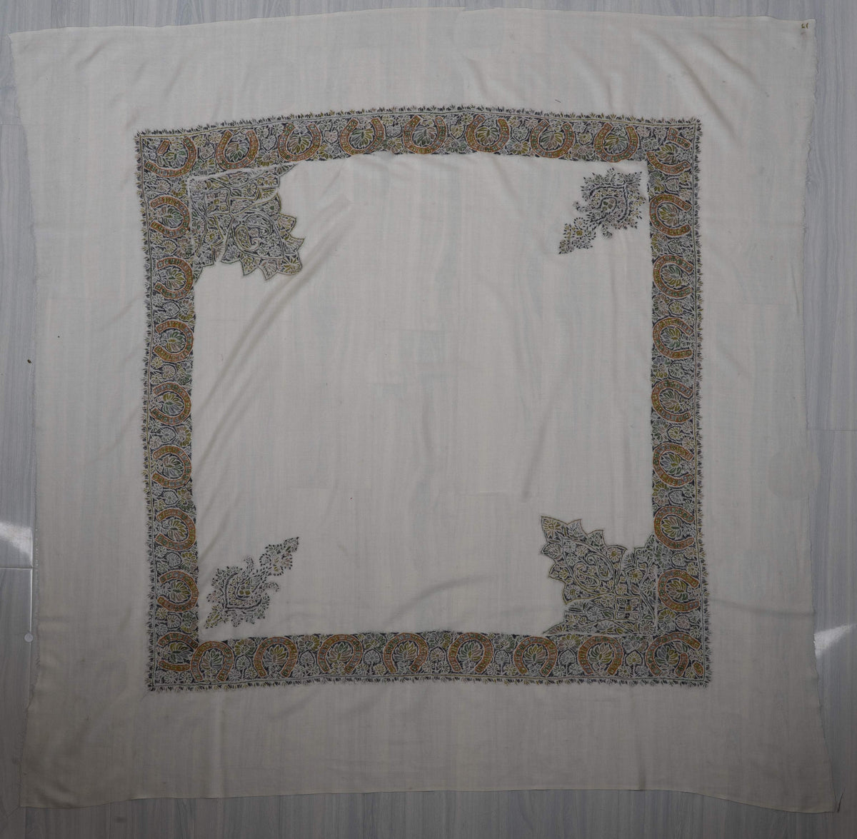 Ivory square Merino wool rumal laid flat, with olive and gold paisley borders and four ornate corner motifs