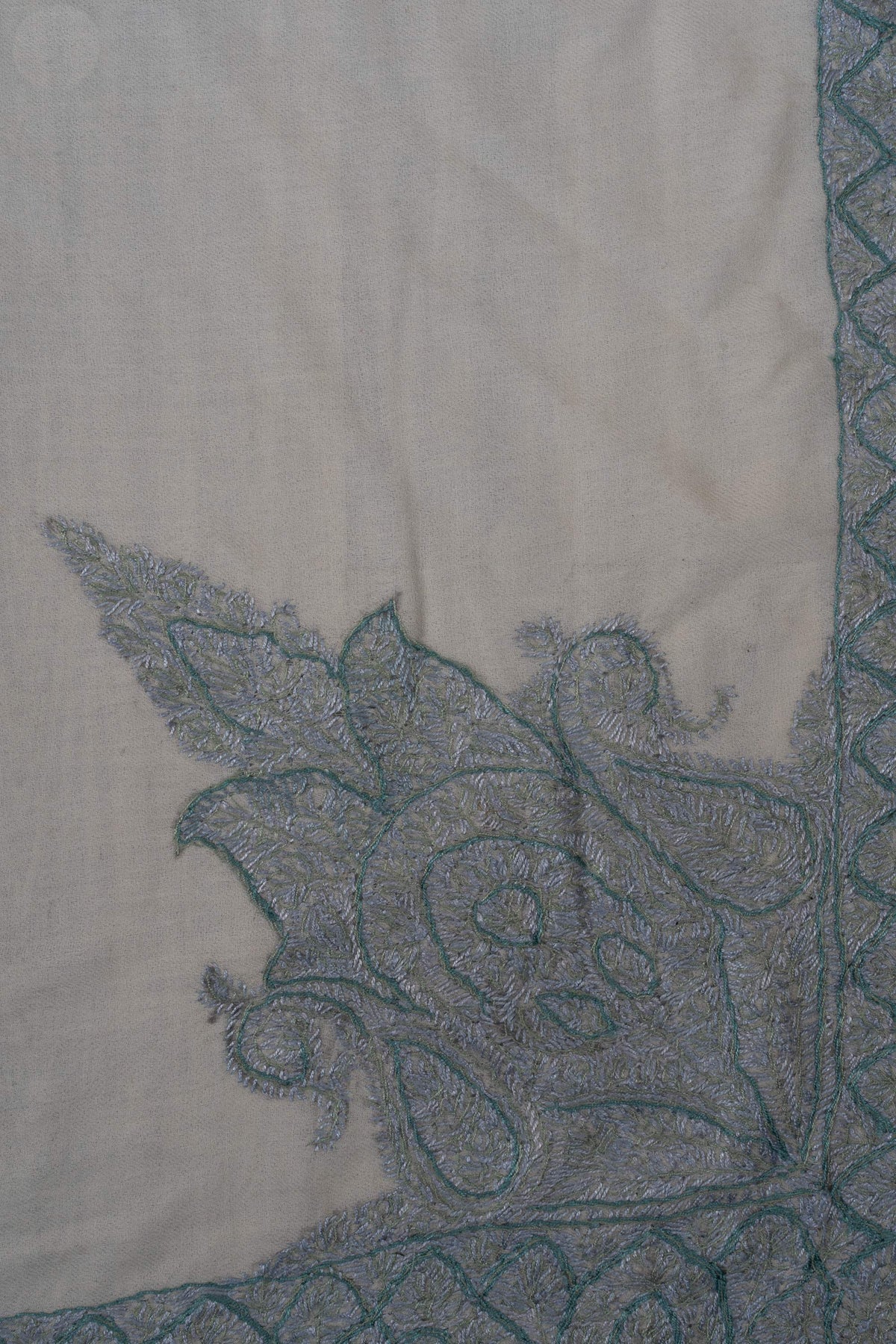 Close-up of pale blue floral embroidery and darker blue outlines within the rumal’s ornate corner motif.