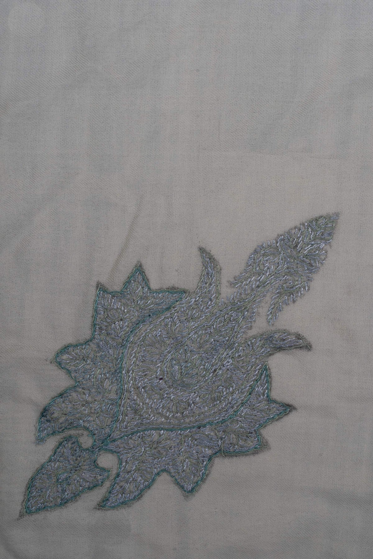 Large icy-blue lotus-like motif embroidered on the ivory rumal.
