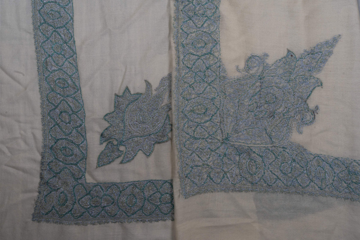 Folded ivory rumal corners displaying both sides of the icy-blue floral embroidery.