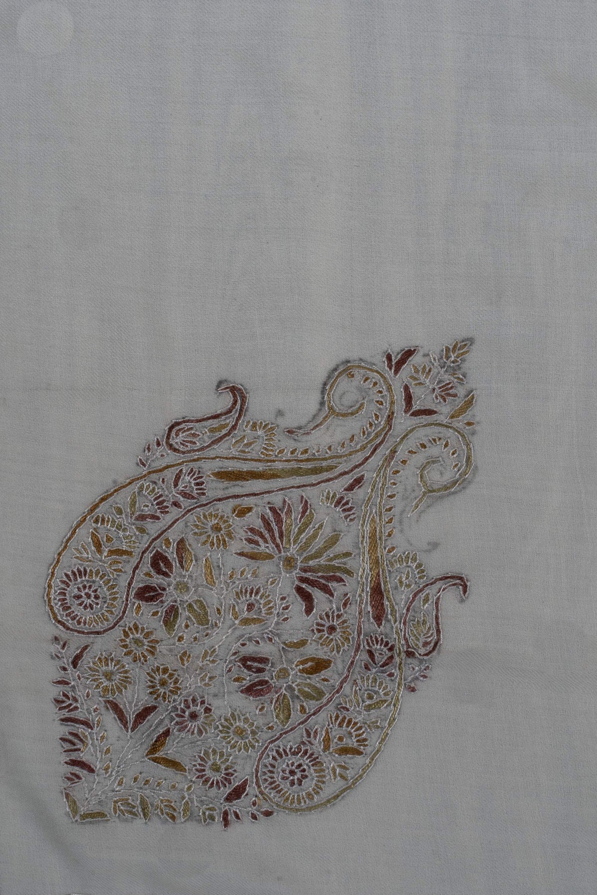 Close-up of an ornate Sozni motif filled with amber, olive and rust flowers and curling stems on ivory Merino wool.