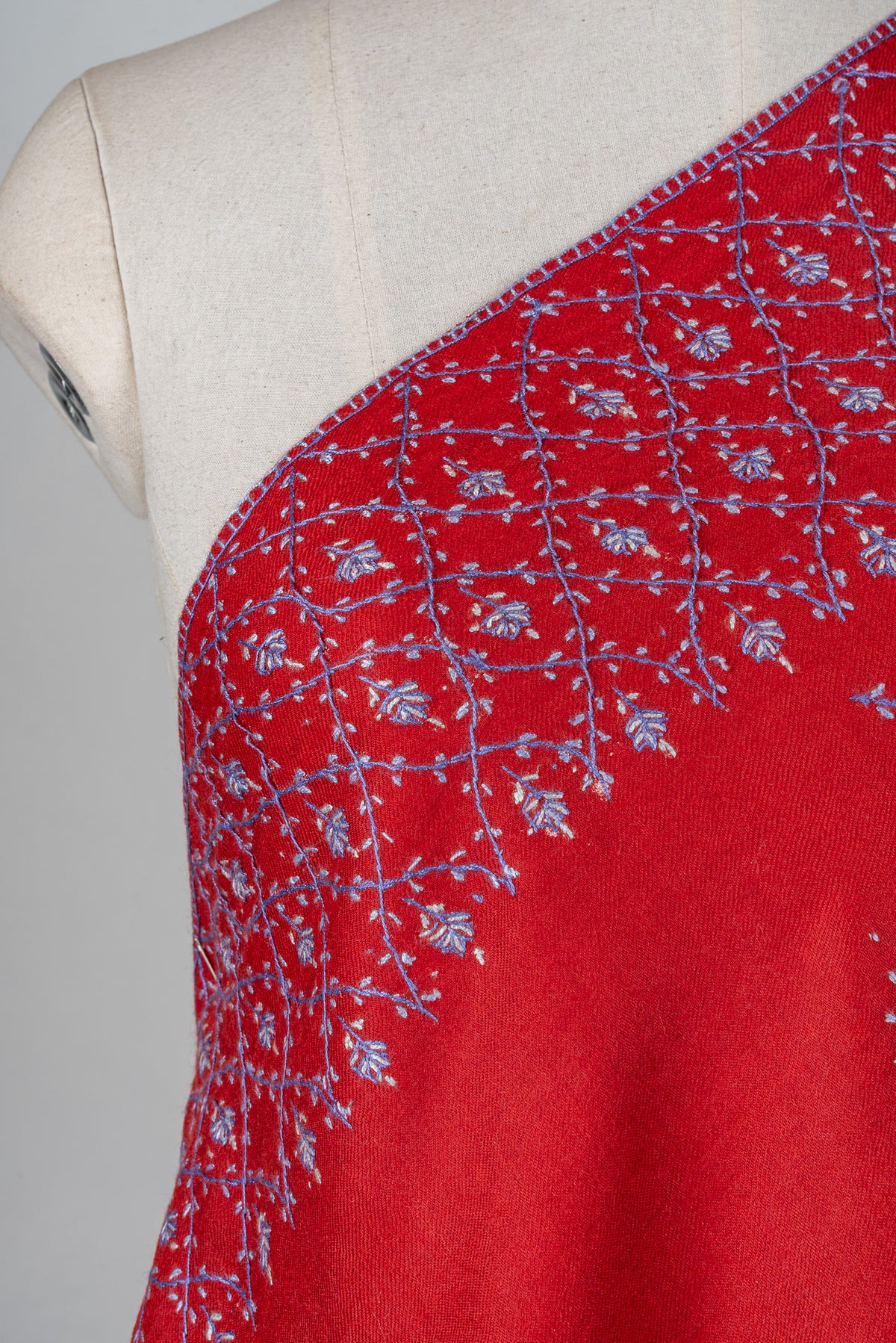 Close-up of pale lavender Sozni floral latticework across the shoulder border of a ruby-red shawl