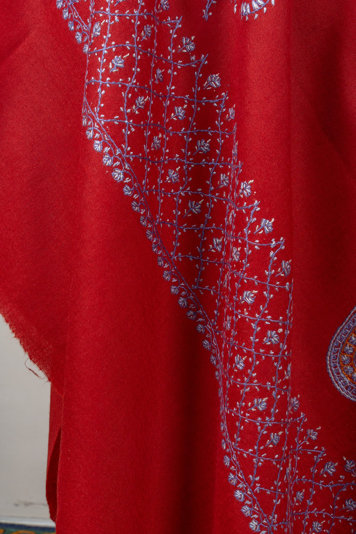Hanging fold of a ruby-red shawl showing a wide band of pale lavender Sozni floral latticework