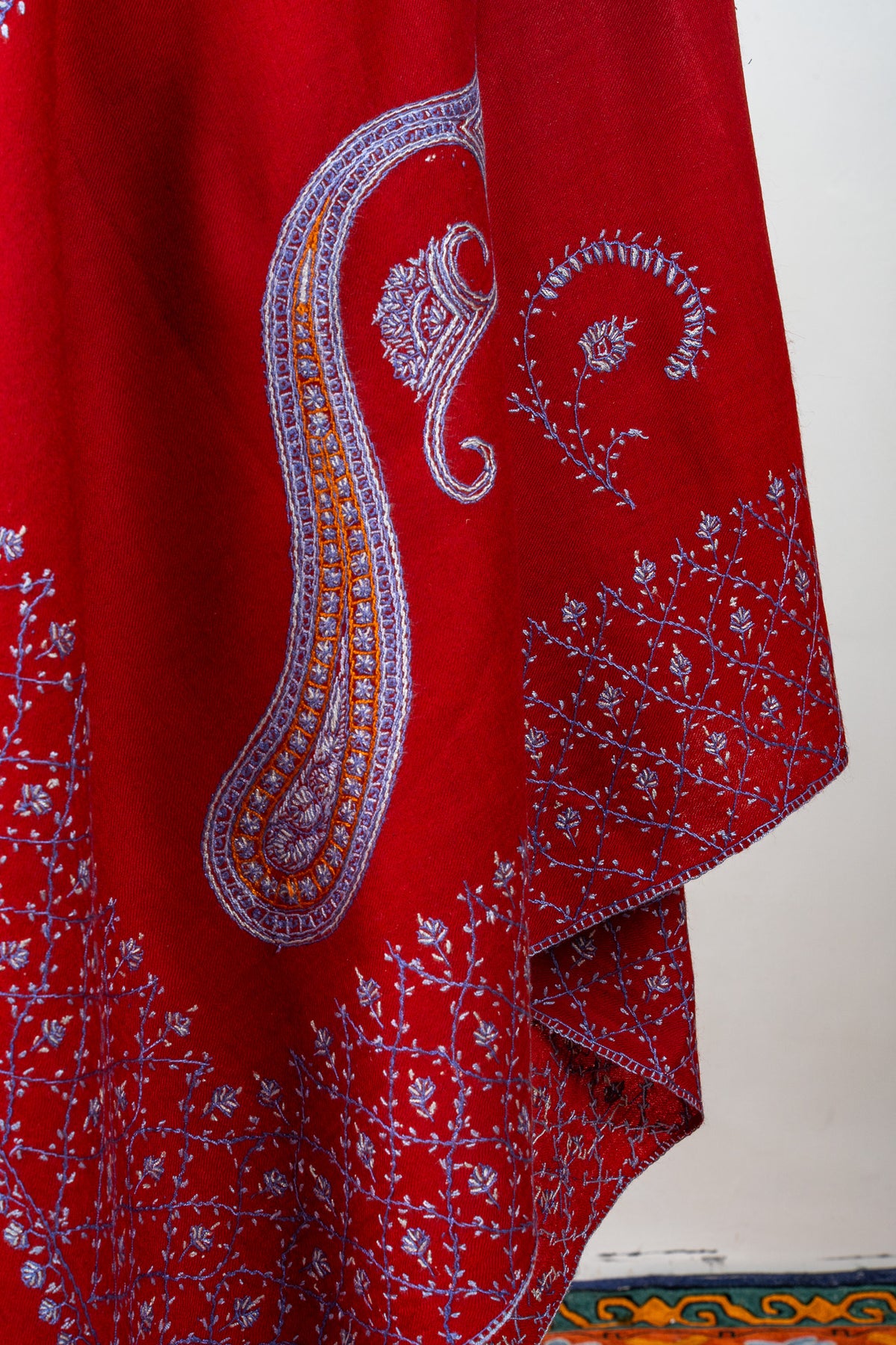 Draped ruby-red shawl showing a large lavender and gold-toned paisley, a curved sprig and floral lattice borders