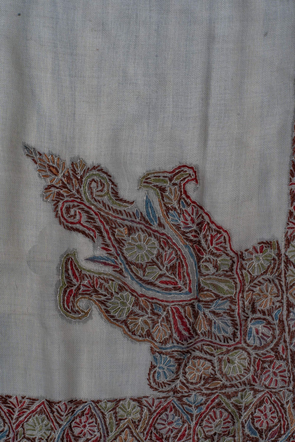 Close-up of the rumal’s large corner paisley filled with muted red, blue and green floral details.