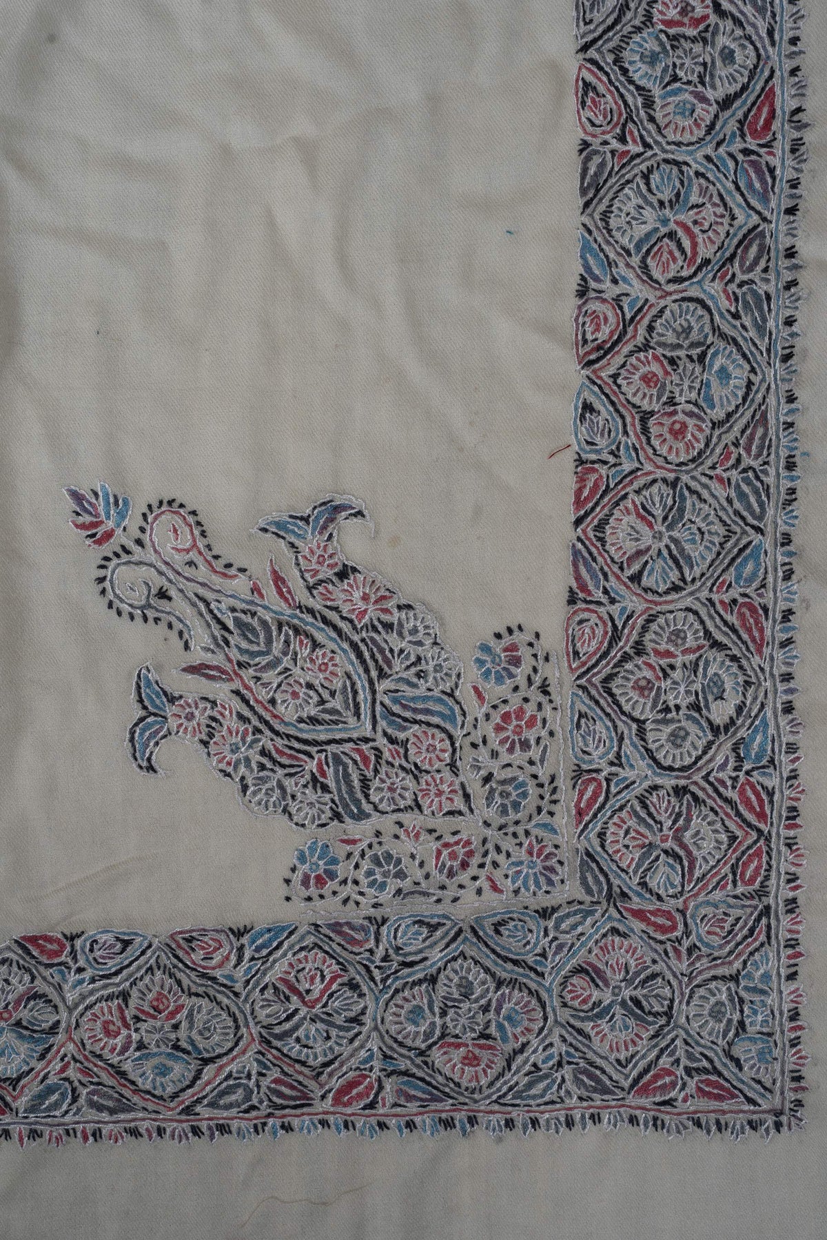 Ivory rumal corner with a large blue and pink floral design rising from the patterned border