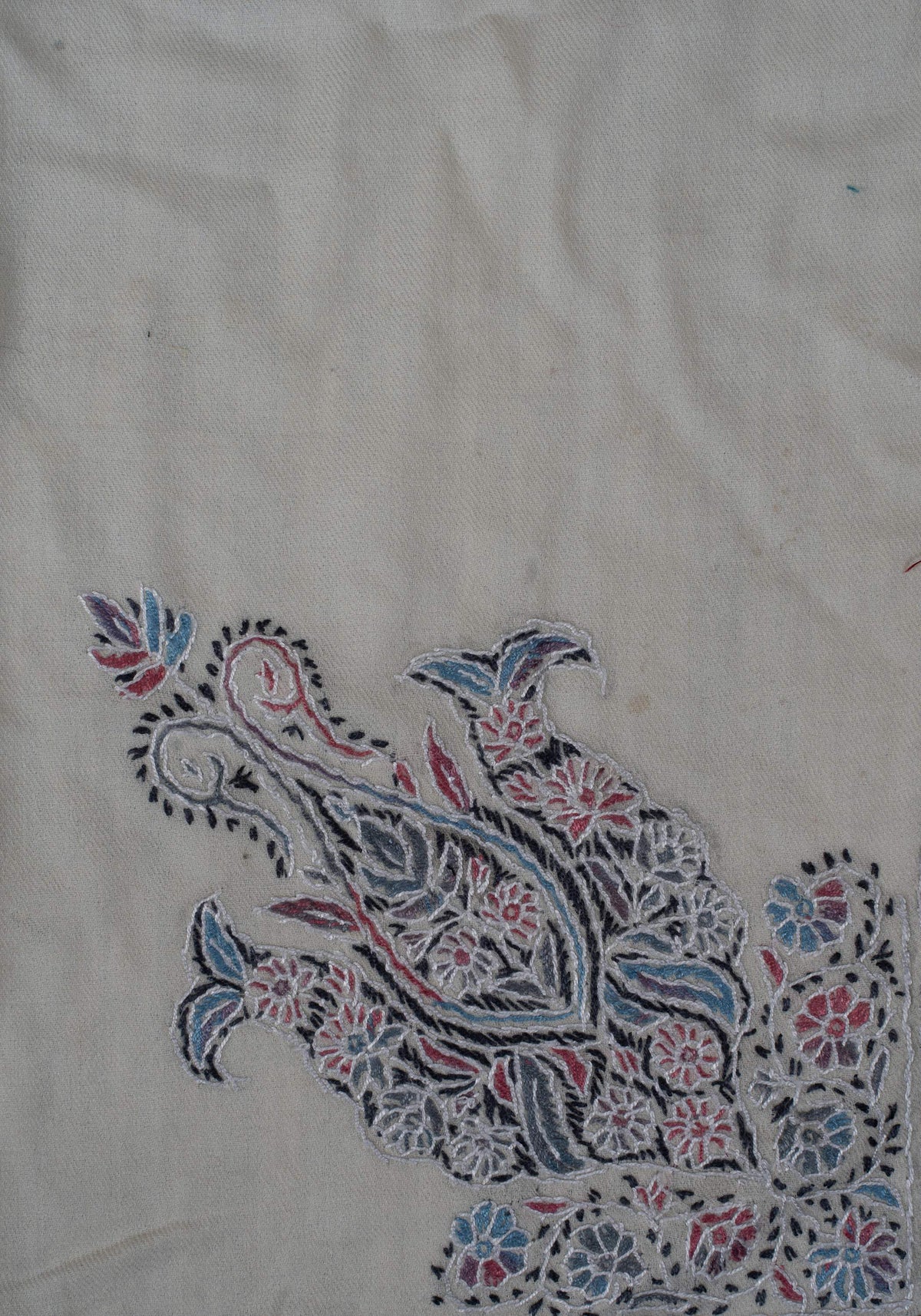 Close-up of the large corner motif with blue flowers, pink accents and curled tips on ivory wool
