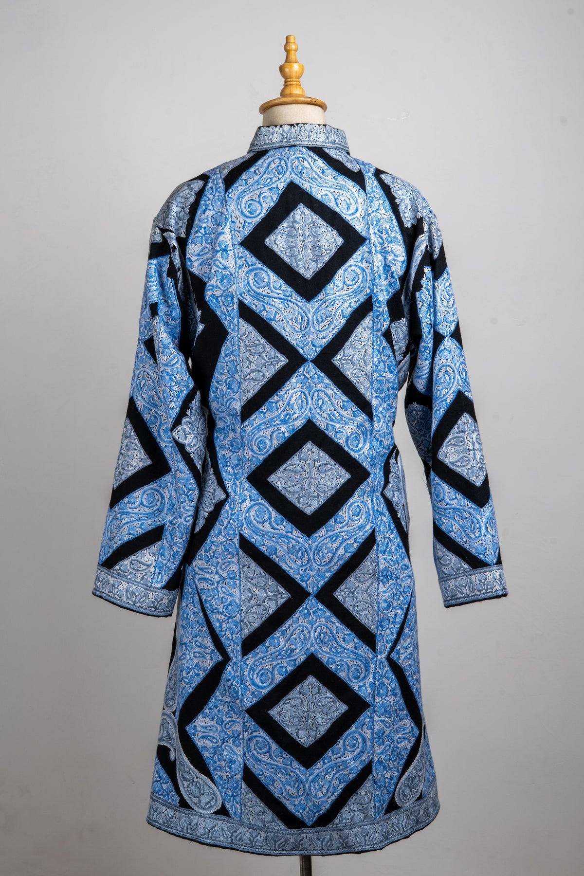 Back of an ice-blue Aari jacket, with large black-outlined diamonds and crosses over pale paisley-and-floral embroidery