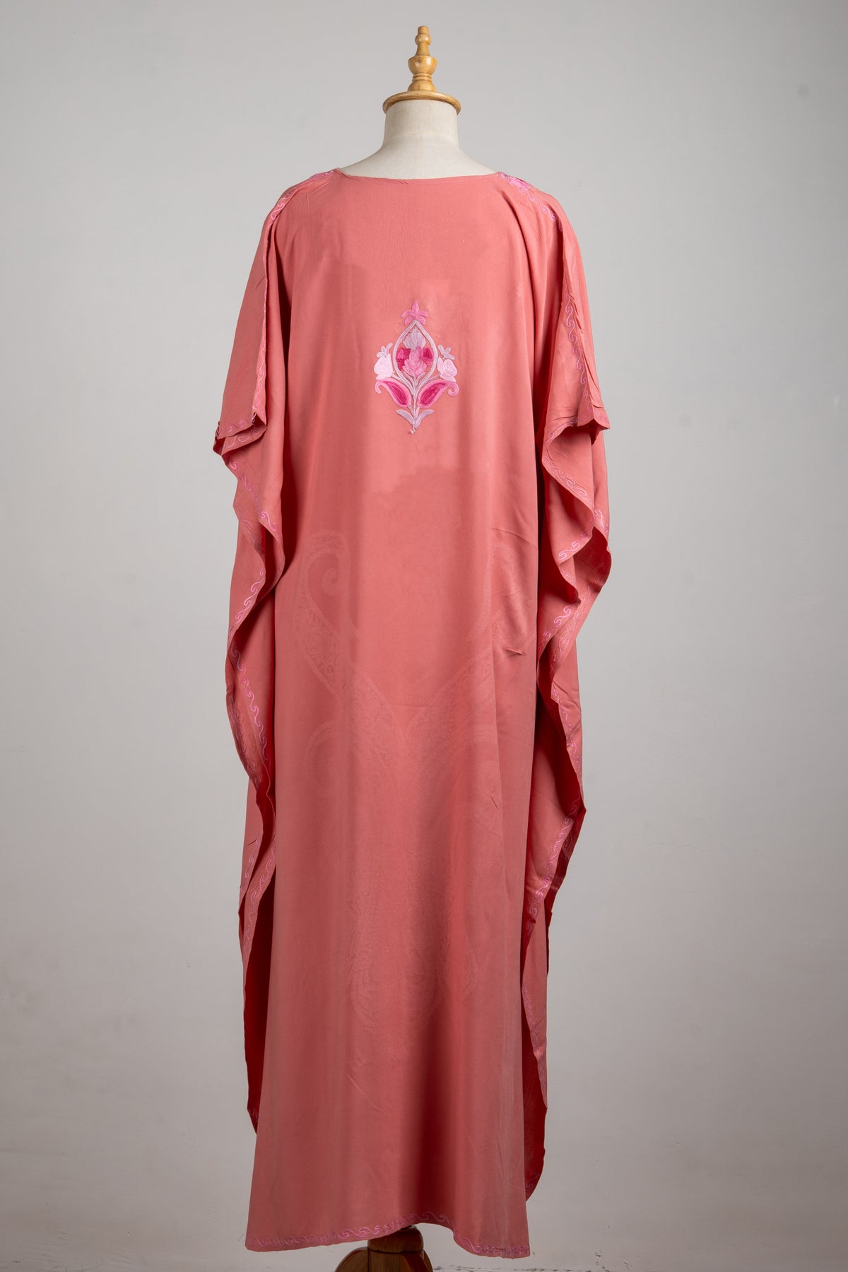 Back of the rose-pink kaftan, showing loose draped sleeves and a small pointed floral motif between the shoulders
