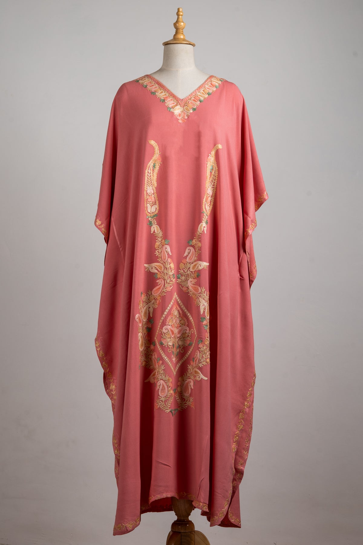 Full front view of a blush-rose kaftan, with long champagne embroidered motifs and a narrow decorative hem edge