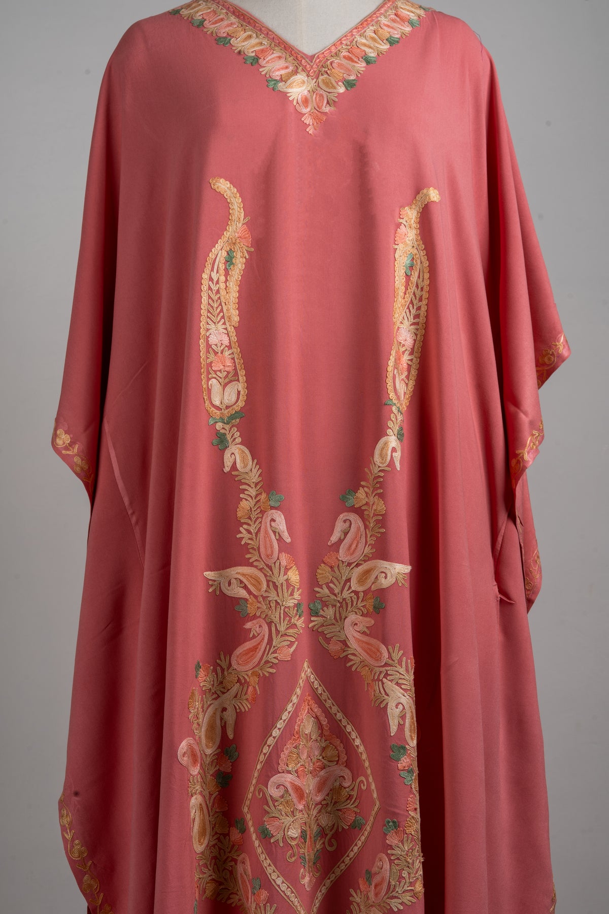 Detail of the kaftan’s champagne and peach paisleys, green accents and central diamond-shaped floral motif