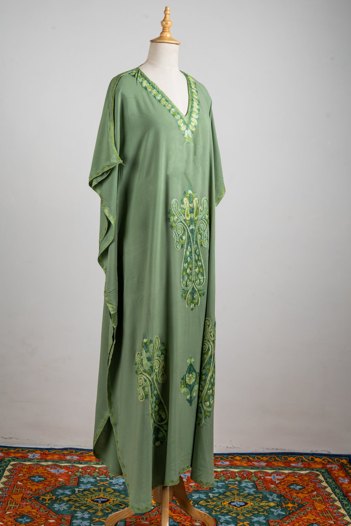 Angled full-length olive-green kaftan with an embroidered V-neck and ornate green and lemon Aari crests down the front