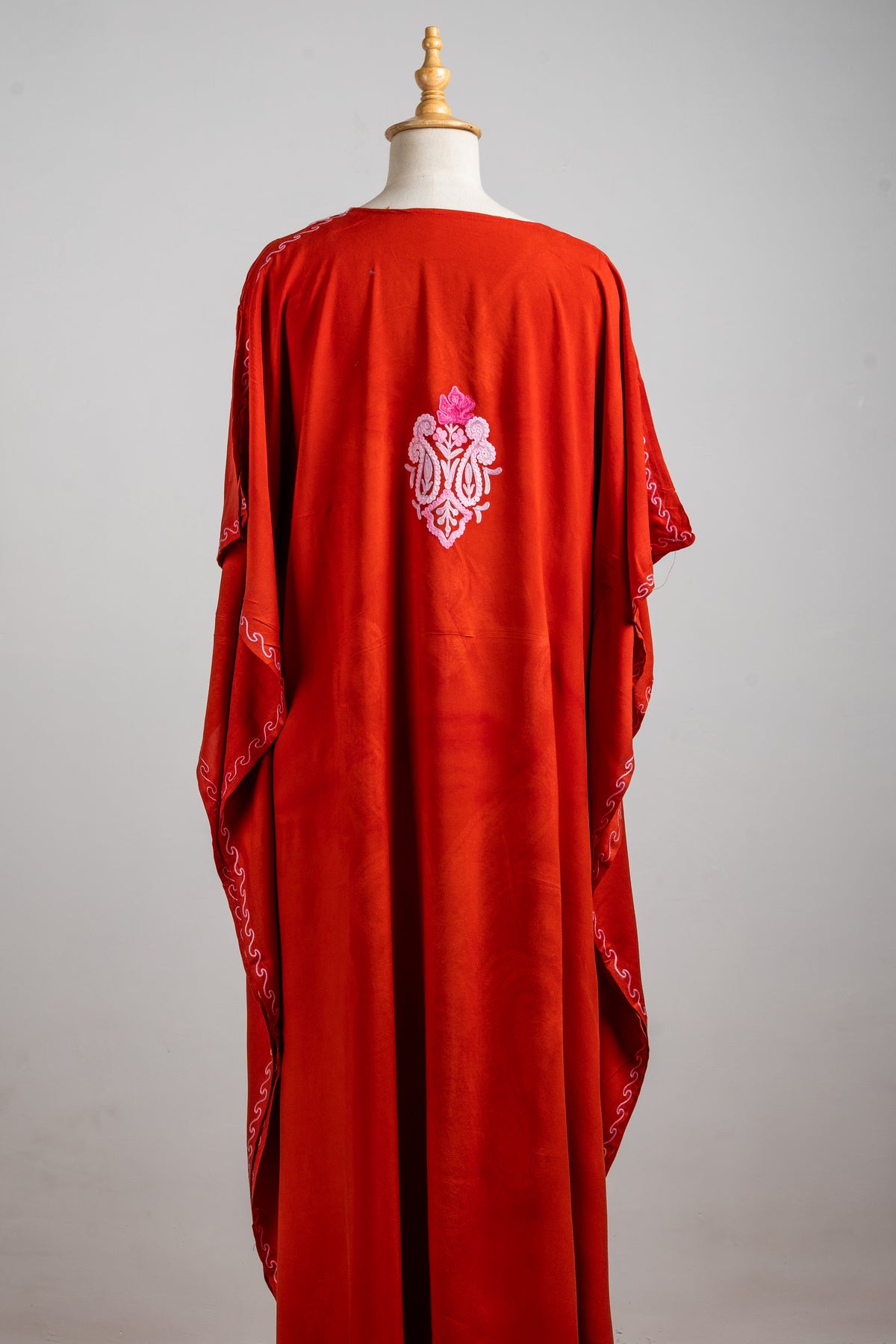 Full back view of the crimson kaftan with a single pink ornamental motif and fine embroidered edging on the sleeves.