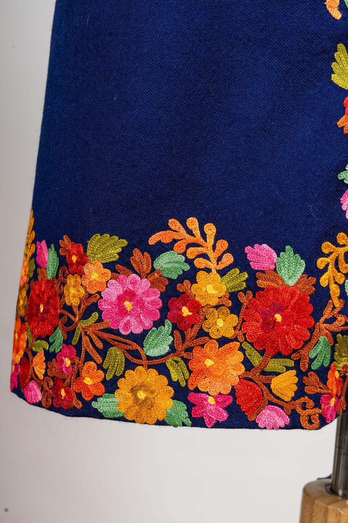 Close view of the navy jacket’s lower floral border with red, pink and yellow flowers and green leaves