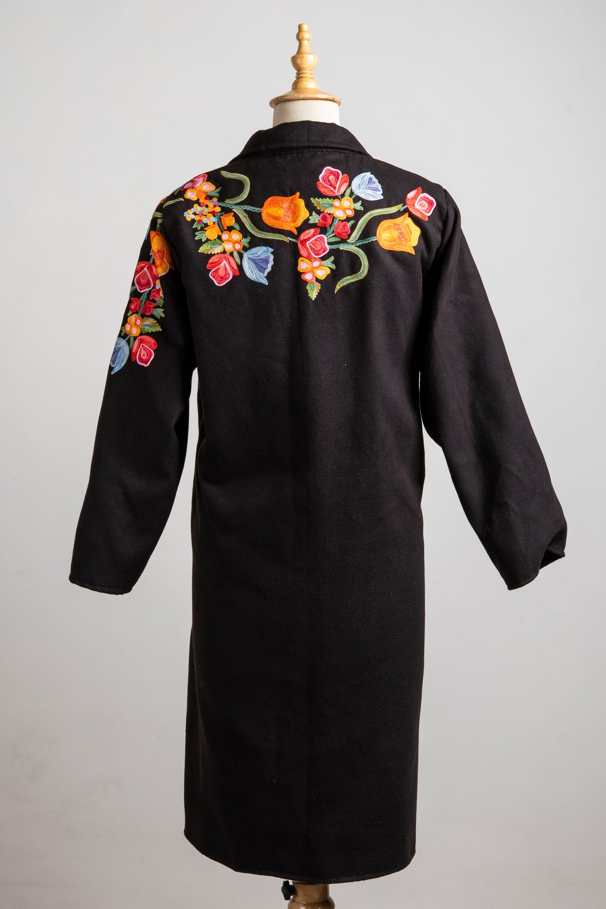 Full back view of the black longline blazer with colourful floral embroidery across the shoulders and a mostly plain body.