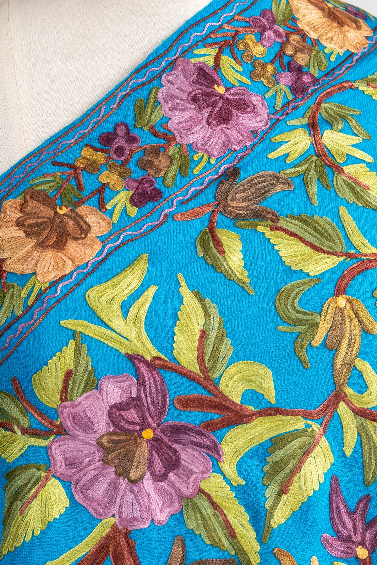 Close-up of lavender and mustard flowers, green leaves and rust-coloured stems along the peacock-blue stole’s border