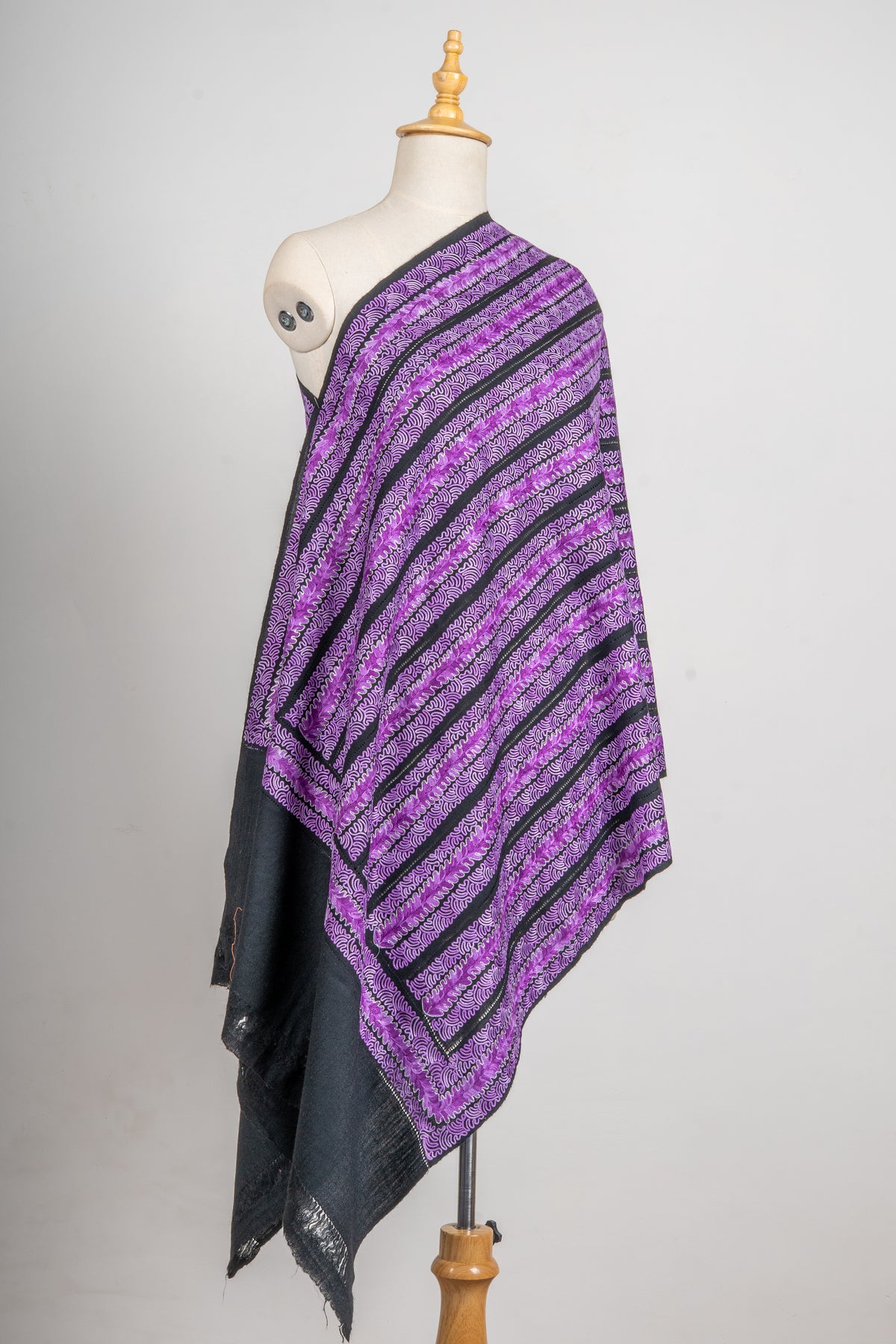 Full draped view of the charcoal stole with purple embroidered stripes, a framed border and a broad dark end panel.