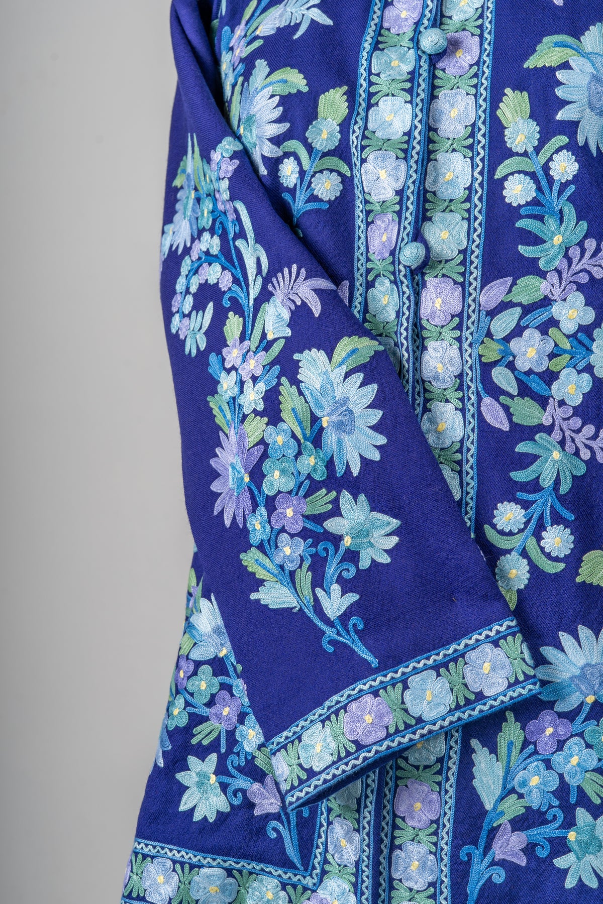 Detail of the indigo jacket’s crossed sleeve, floral cuff border and embroidered button placket