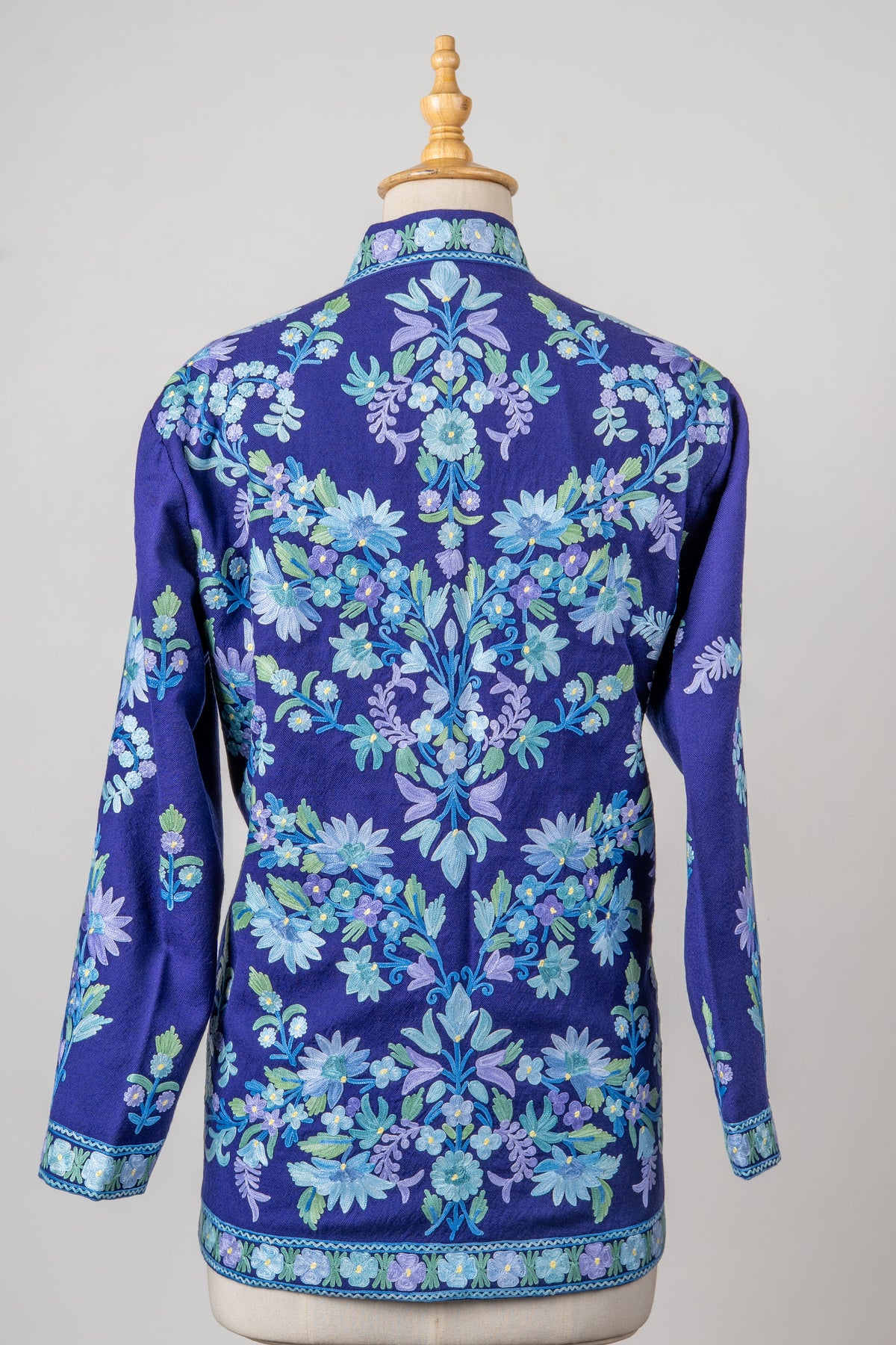 Back view of the indigo short jacket with symmetrical blue and lavender floral vines, embroidered cuffs and hem