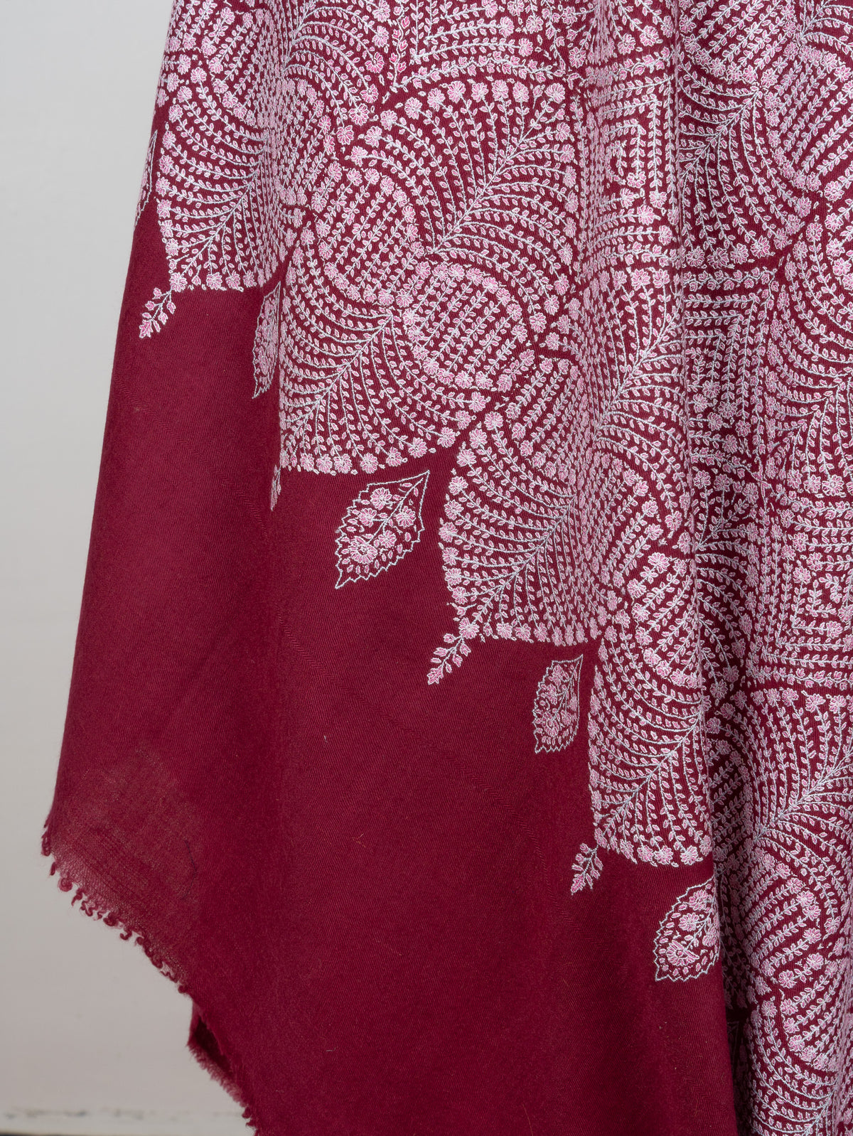 Detail of the wine shawl's hanging folds, with a scalloped embroidered border and pale teardrop motifs above the plain end
