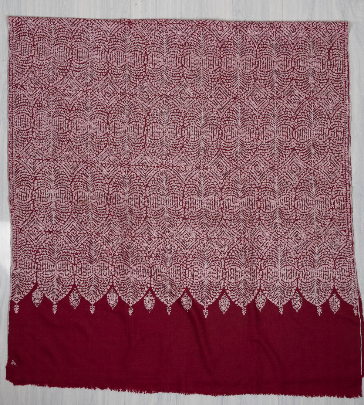 Wine Pashmina shawl laid flat, with pale circular floral embroidery ending in a scalloped border above the plain fabric