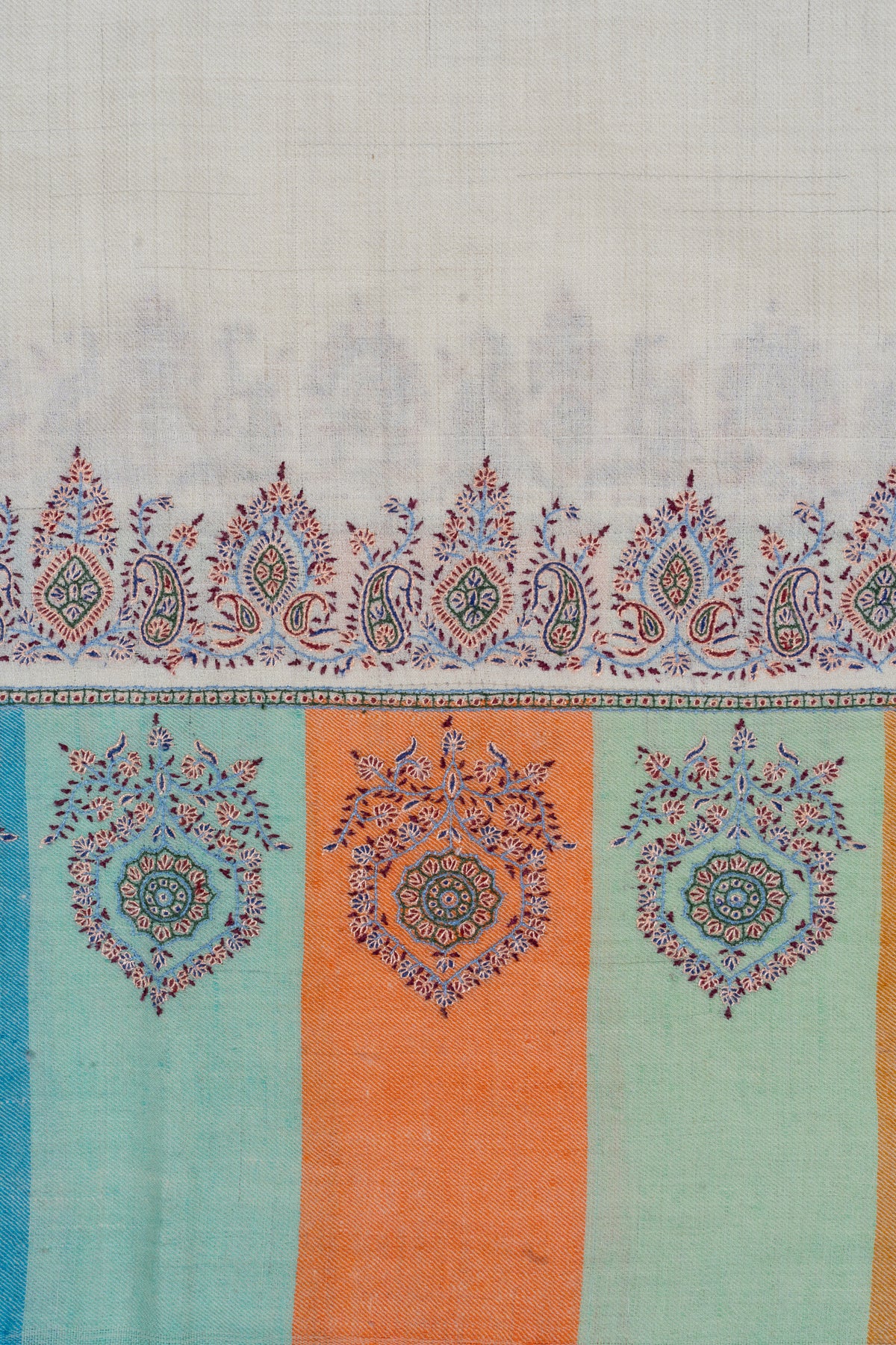 Close-up of ornate motifs on mint and orange end panels beneath the ivory shawl's paisley border