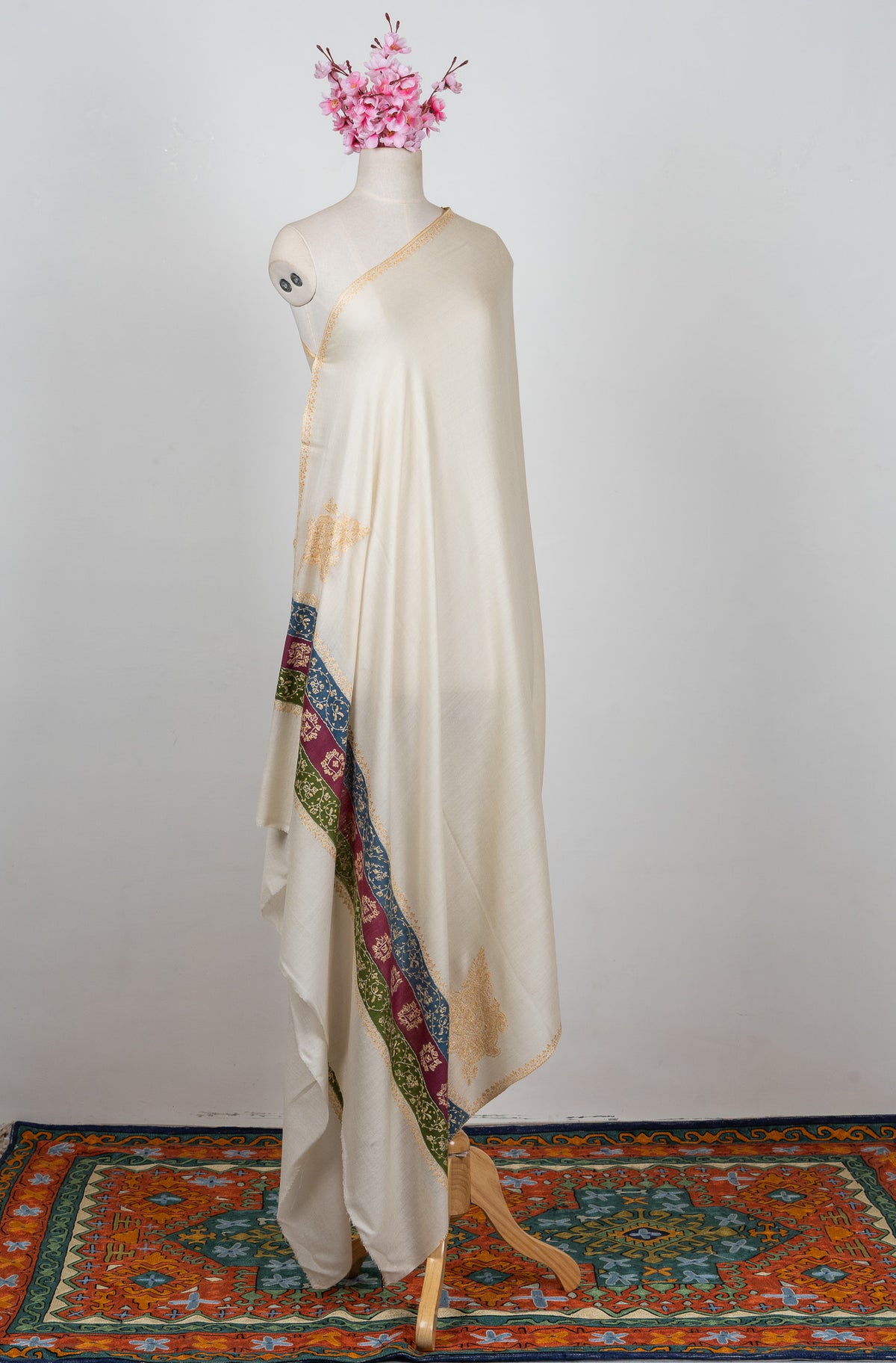 Full-length ivory shawl on a mannequin with pale golden edging and a multicoloured Sozni floral end border