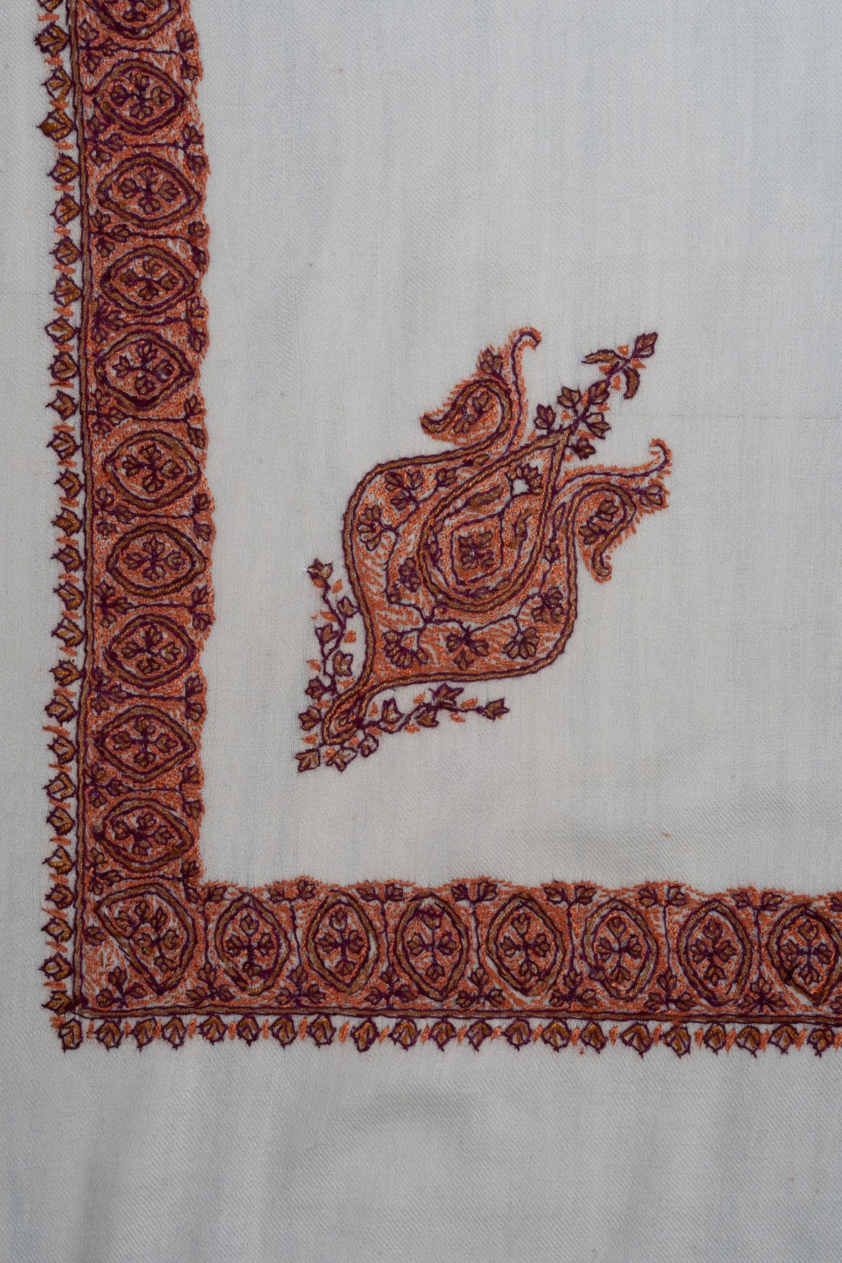 Ivory rumal corner with a cinnamon-toned Sozni motif framed by a narrow border of floral medallions