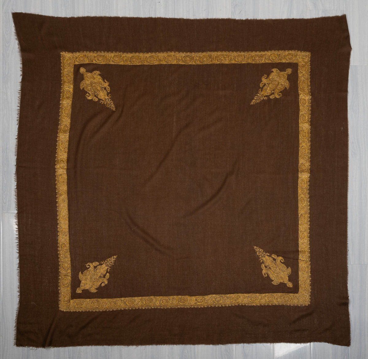 Square umber-brown Merino wool rumal laid flat, with golden floral borders and four ornate paisley corner motifs