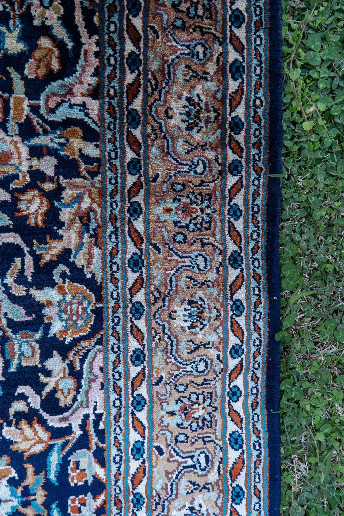 Detail of the carpet's pink and blue floral side border beside its dark floral field